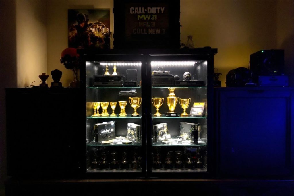 Étagères vitrées illuminées avec trophées et affiches de jeu
