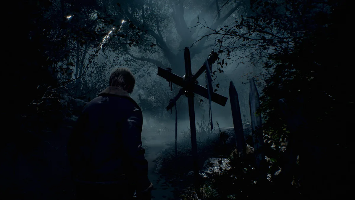 Leon S. Kennedy de dos sur un chemin forestier brumeux près d'une croix en bois dans Resident Evil 4 (2023)